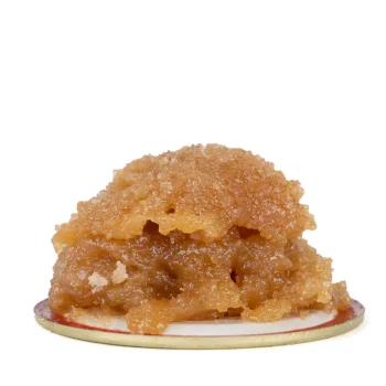 Close-up image of frosted fruit cake live resin with a golden amber hue and sticky texture